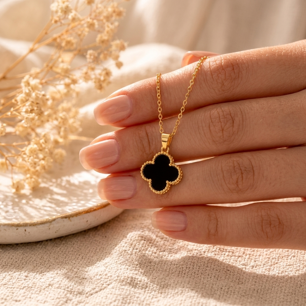Black Clover Gold Necklace pendant close up on cream linen with dried flowers
