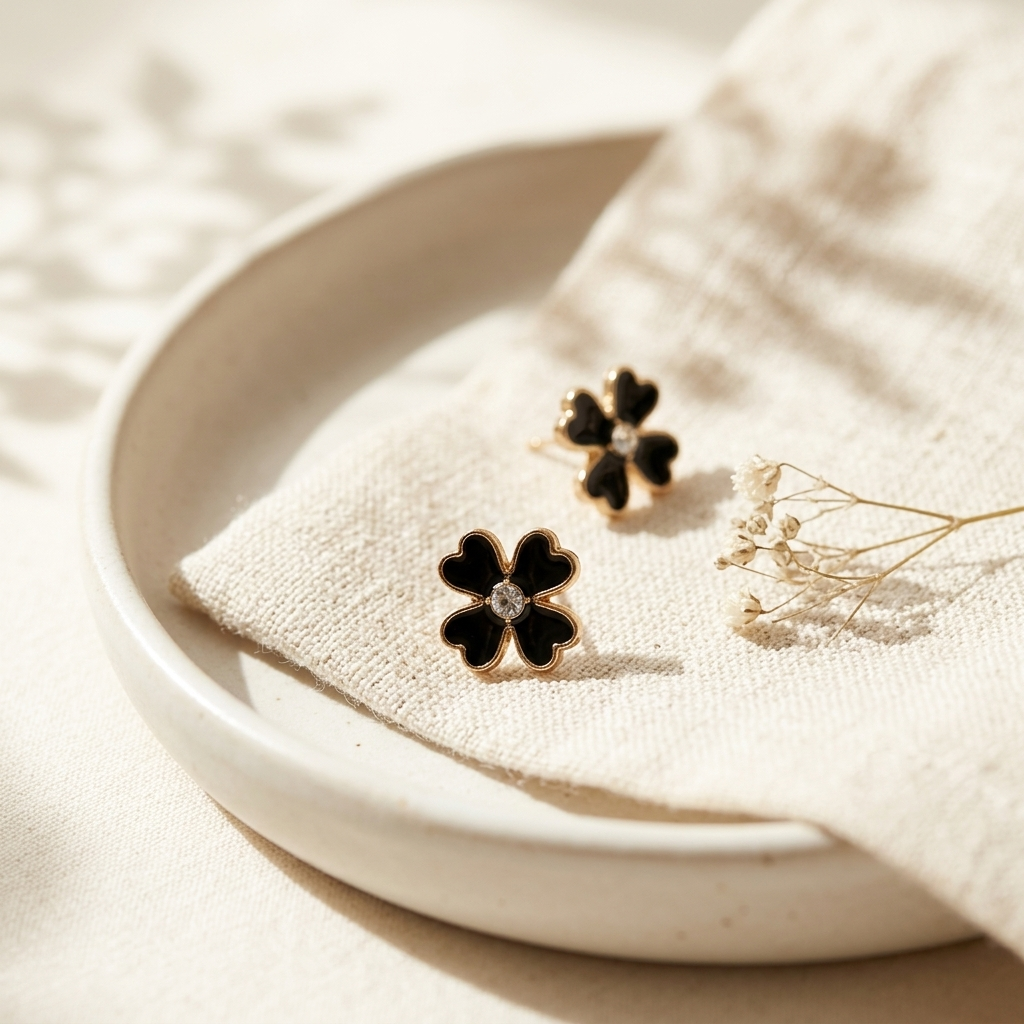 Black Clover Gold Stud Earrings held in hand showing milgrain border detail