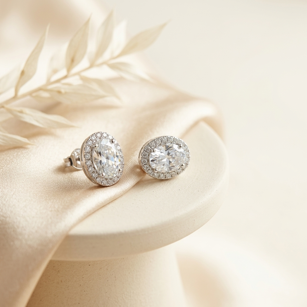 Silver Oval Halo Crystal Stud Earrings on cream silk surface