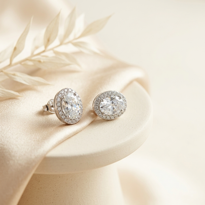 Silver Oval Halo Crystal Stud Earrings on cream silk surface